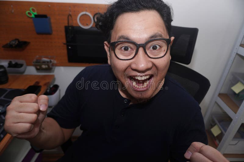 Uomo asiatico urla allegramente di gioia di vincere. imprenditore di successo che lavora a casa fotografia stock
