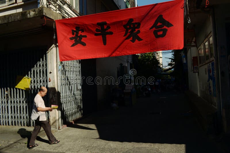 Uomo asiatico vicino al manifesto rosso con i geroglifici cinesi immagine stock libera da diritti Uomo asiatico vicino al manifesto rosso con i geroglifici cinesi immagine stock libera da diritti