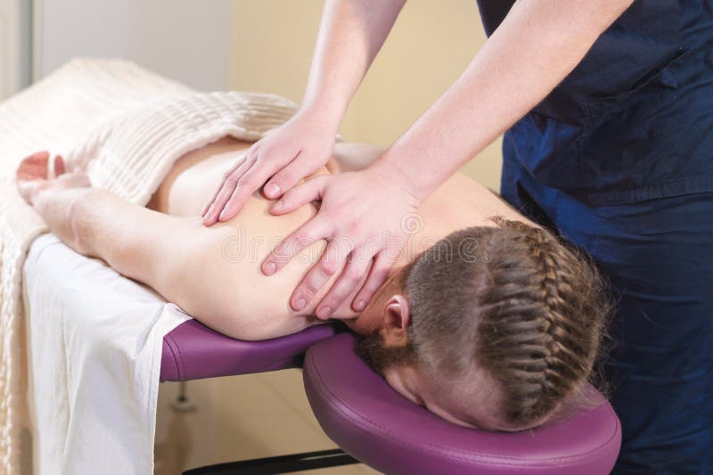 Uomo barbuto rilassato con un taglio di capelli alla moda al ricevimento al chiropratico Procedura di massaggio di benessere fotografia stock libera da diritti Uomo barbuto rilassato con un taglio di capelli alla moda al ricevimento al chiropratico Procedura di massaggio di benessere fotografia stock libera da diritti