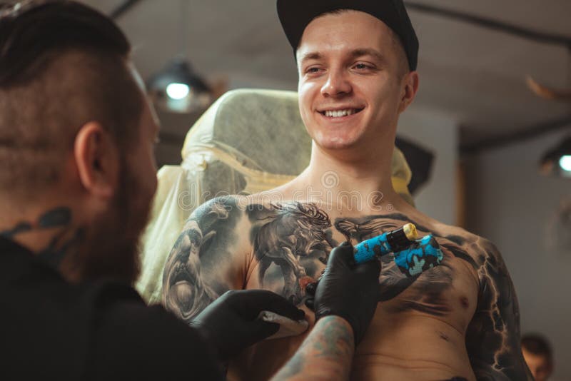Uomo bello che ottiene un tatuaggio allo studio alternativo di arte immagine stock libera da diritti Uomo bello che ottiene un tatuaggio allo studio alternativo di arte immagine stock libera da diritti
