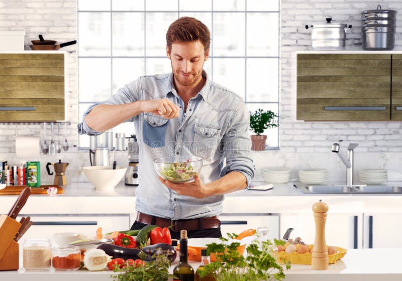 Uomo bello che prepara insalata in cucina fotografia stock Uomo bello che prepara insalata in cucina fotografia stock