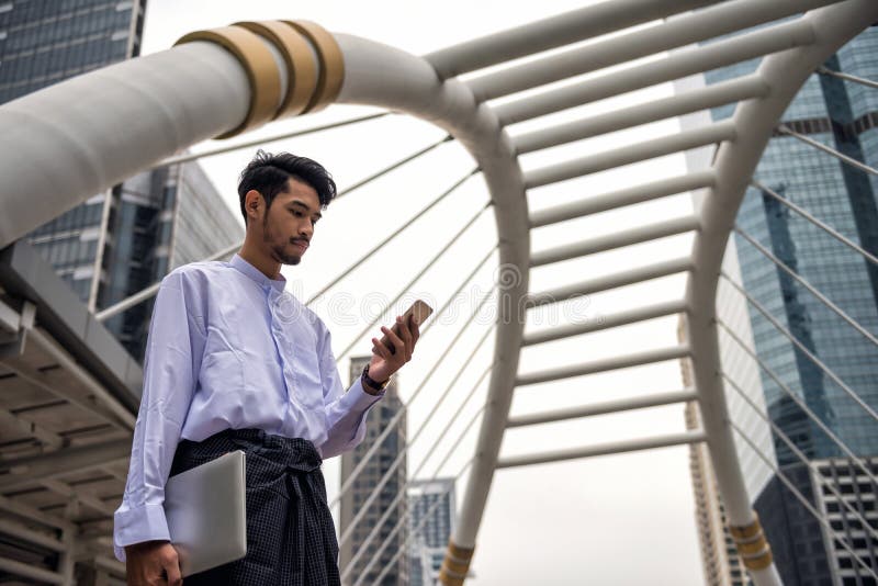 Uomo birmano del Myanmar che utilizza smartphone nella città moderna fotografie stock libere da diritti Uomo birmano del Myanmar che utilizza smartphone nella città moderna fotografie stock libere da diritti