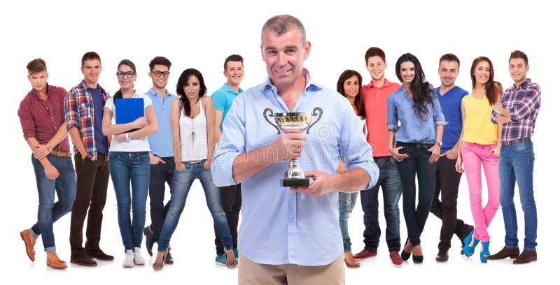 Uomo casuale anziano che tiene una tazza del trofeo davanti al gruppo di conquista immagine stock Uomo casuale anziano che tiene una tazza del trofeo davanti al gruppo di conquista immagine stock