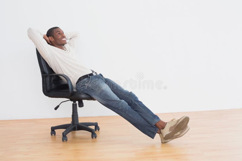 Uomo casuale premuroso che si siede sulla sedia dell'ufficio nella stanza vuota fotografie stock Uomo casuale premuroso che si siede sulla sedia dell'ufficio nella stanza vuota fotografie stock