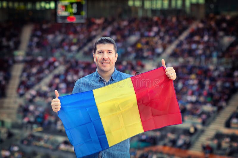 Uomo caucasico felice che tiene bandiera nazionale rumena in mani sostenitore al †internazionale di avvenimento sportivo «ad in fotografia stock libera da diritti Uomo caucasico felice che tiene bandiera nazionale rumena in mani sostenitore al †internazionale di avvenimento sportivo «ad in fotografia stock libera da diritti