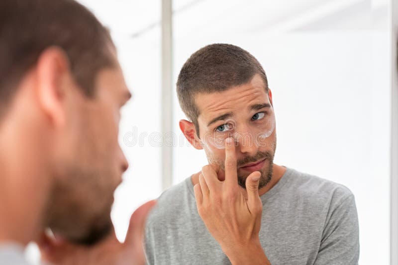 Uomo che applica idratante sotto gli occhi fotografia stock libera da diritti Uomo che applica idratante sotto gli occhi fotografia stock libera da diritti
