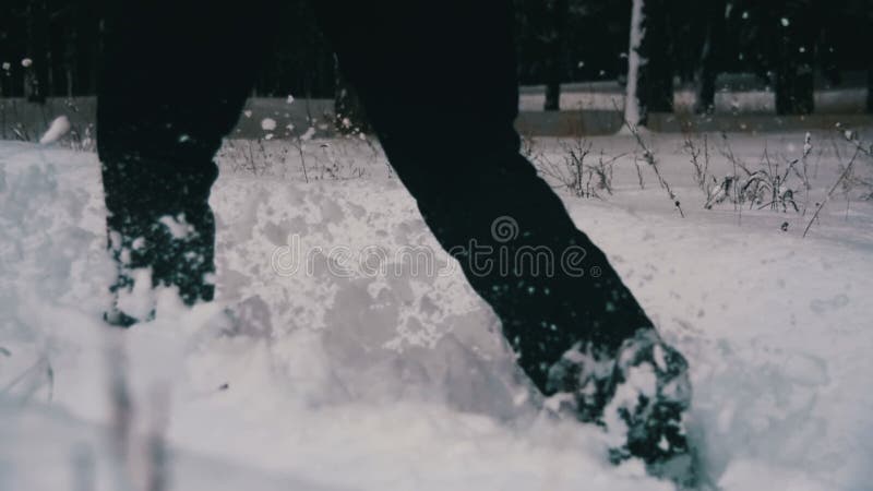 Uomo che cammina nella neve profonda nella foresta di inverno al giorno di Snowy Movimento lento