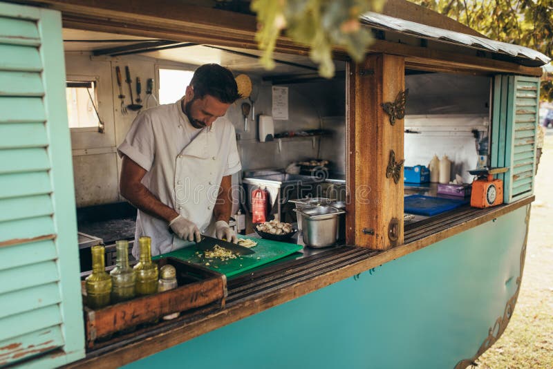 Uomo che cucina in un camion mobile dell'alimento immagini stock libere da diritti Uomo che cucina in un camion mobile dell'alimento immagini stock libere da diritti