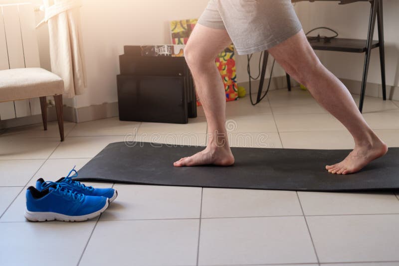 Uomo che fa esercizio del corpo e che risolve a casa immagine stock