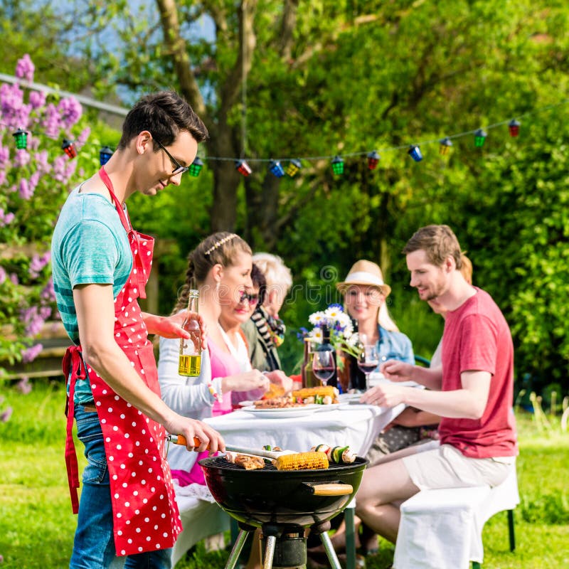 Uomo che griglia carne sul partito del barbecue del giardino immagine stock Uomo che griglia carne sul partito del barbecue del giardino immagine stock