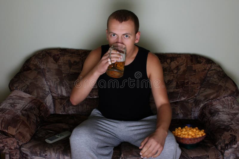 Uomo che guarda TV e che beve birra immagini stock Uomo che guarda TV e che beve birra immagini stock