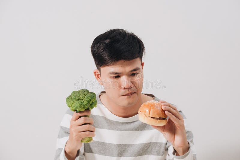 Uomo che ha scelta dura fra alimento sano e non sano immagine stock libera da diritti Uomo che ha scelta dura fra alimento sano e non sano immagine stock libera da diritti
