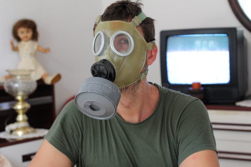 Uomo che indossa la retro maschera antigas a casa immagine stock Uomo che indossa la retro maschera antigas a casa immagine stock