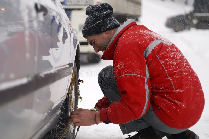Uomo che installa le catene di neve immagini stock libere da diritti Uomo che installa le catene di neve immagini stock libere da diritti