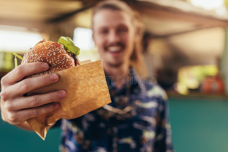 Uomo che offre un hamburger del camion dell'alimento fotografia stock Uomo che offre un hamburger del camion dell'alimento fotografia stock