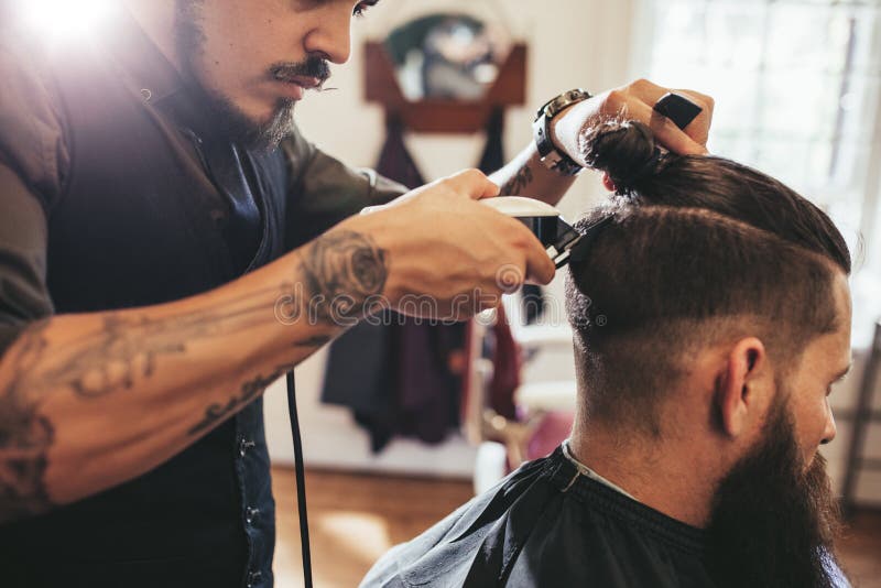 Uomo che ottiene taglio di capelli d'avanguardia nel negozio di barbiere fotografia stock Uomo che ottiene taglio di capelli d'avanguardia nel negozio di barbiere fotografia stock