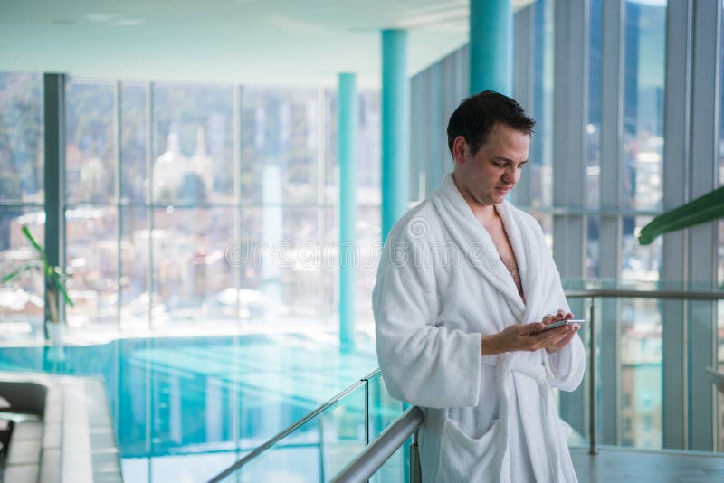 Uomo che per mezzo del cellulare vicino alla piscina dell'interno fotografia stock libera da diritti Uomo che per mezzo del cellulare vicino alla piscina dell'interno fotografia stock libera da diritti