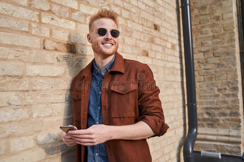 Uomo Che Porta Occhiali Da Sole in Piedi Vicino Al Muro Di Mattoni E Guarda  Lontano Immagine Stock - Immagine di capelli, lifestyle: 221125535