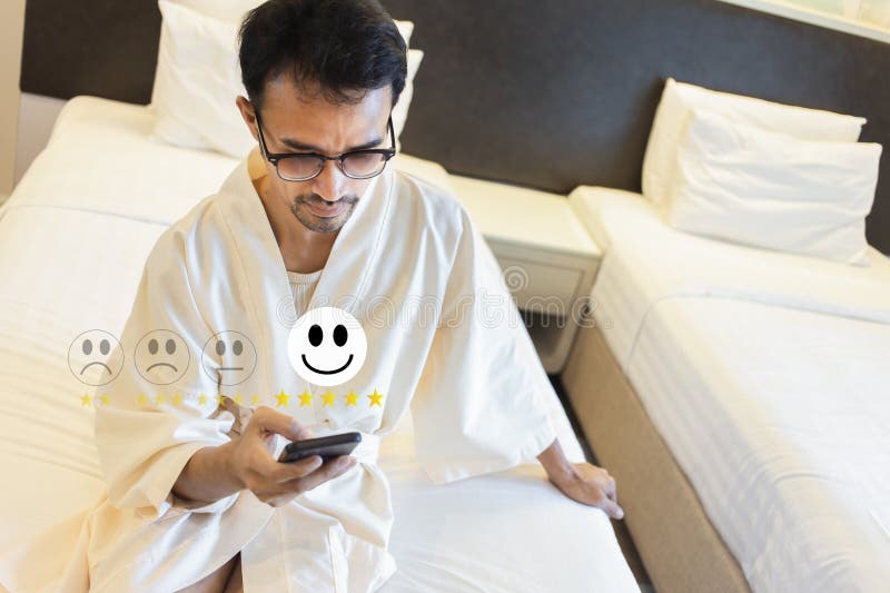 Uomo che prema felice con cinque stelle per una stanza da letto di recensione o hotel immagine stock