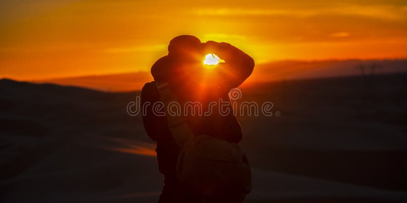 Uomo che prende un'immagine delle dune di sabbia e di tramonto fotografia stock Uomo che prende un'immagine delle dune di sabbia e di tramonto fotografia stock