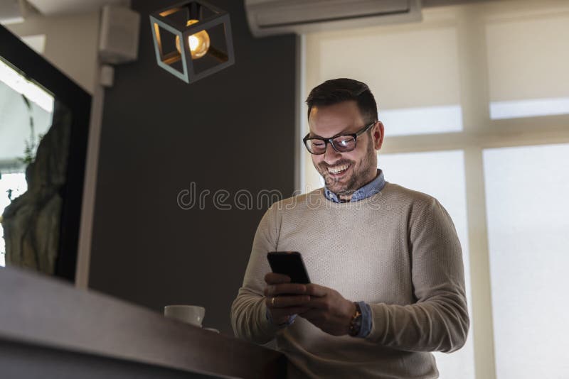 Handsome man standing in a restaurant, typing a text message on a smart phone. Handsome man standing in a restaurant, typing a text message on a smart phone