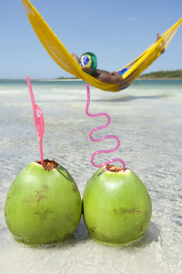Uomo che si rilassa in spiaggia brasiliana dell'amaca con le noci di cocco fotografia stock Uomo che si rilassa in spiaggia brasiliana dell'amaca con le noci di cocco fotografia stock