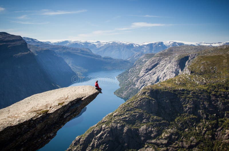 Uomo che si siede sul trolltunga in Norvegia