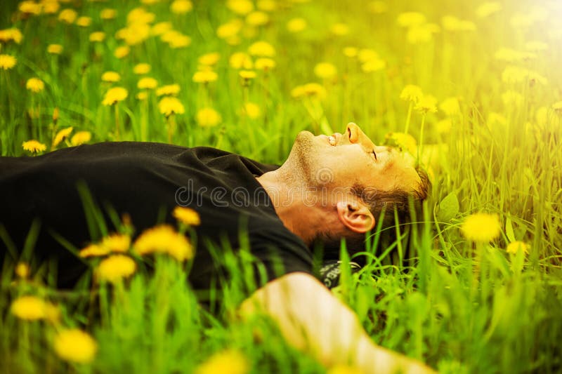 Uomo che si trova sull'erba al giorno soleggiato immagini stock libere da diritti Uomo che si trova sull'erba al giorno soleggiato immagini stock libere da diritti