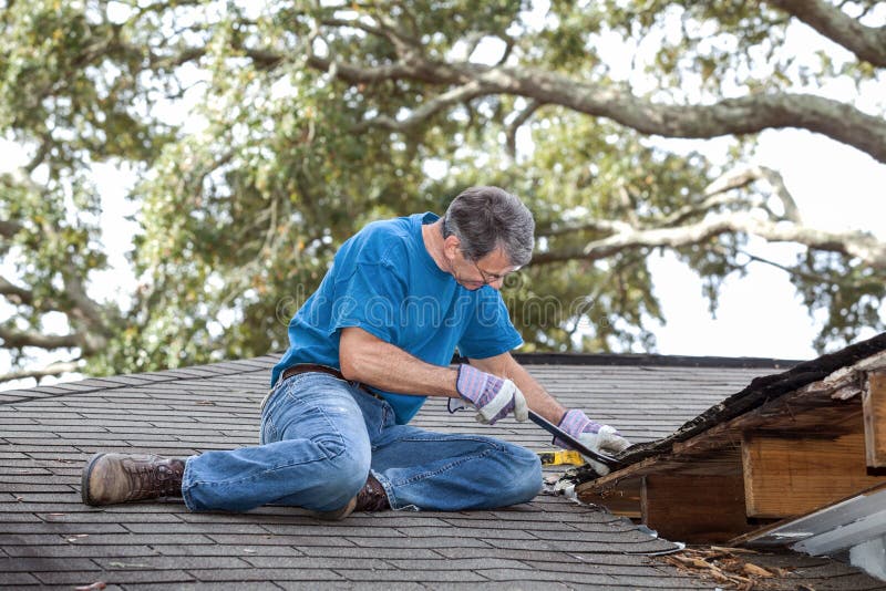 Man using crowbar to remove rotten wood from leaky roof. After removing fascia boards he has discovered that the leak has extended into the beams and decking. Man using crowbar to remove rotten wood from leaky roof. After removing fascia boards he has discovered that the leak has extended into the beams and decking.