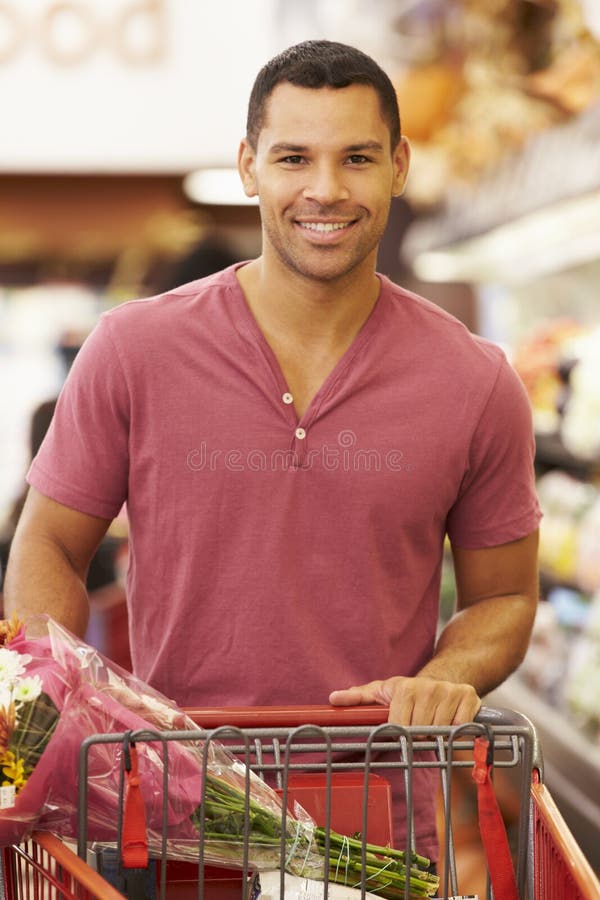 Uomo che spinge carrello dal contatore dei prodotti in supermercato immagini stock libere da diritti Uomo che spinge carrello dal contatore dei prodotti in supermercato immagini stock libere da diritti