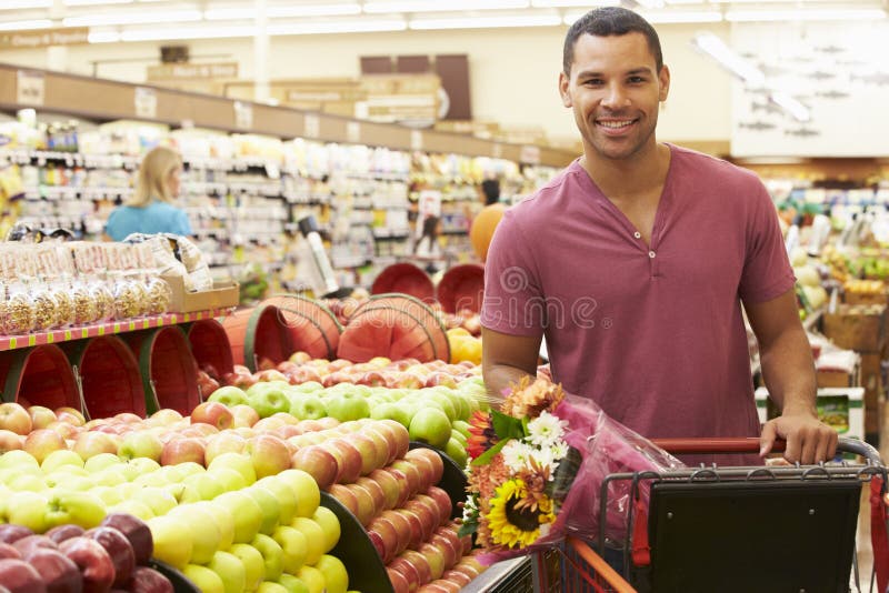 Uomo che spinge carrello dal contatore della frutta in supermercato immagine stock libera da diritti Uomo che spinge carrello dal contatore della frutta in supermercato immagine stock libera da diritti