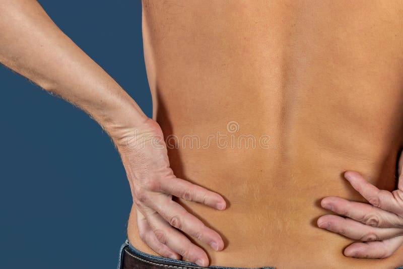 Uomo che tiene il suo lombo infiammato doloroso su fondo blu Sanità e medicina Soffrendo dal dolore alla schiena fotografia stock libera da diritti Uomo che tiene il suo lombo infiammato doloroso su fondo blu Sanità e medicina Soffrendo dal dolore alla schiena fotografia stock libera da diritti