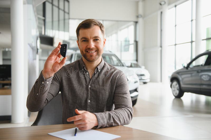 Uomo che tiene la chiave dell'auto nel moderno salone immagini stock libere da diritti