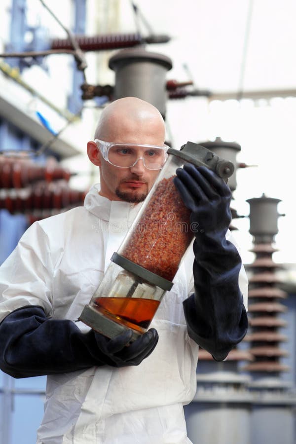 A technician wearing protective clothing holding a large industrial tube or container. A technician wearing protective clothing holding a large industrial tube or container.