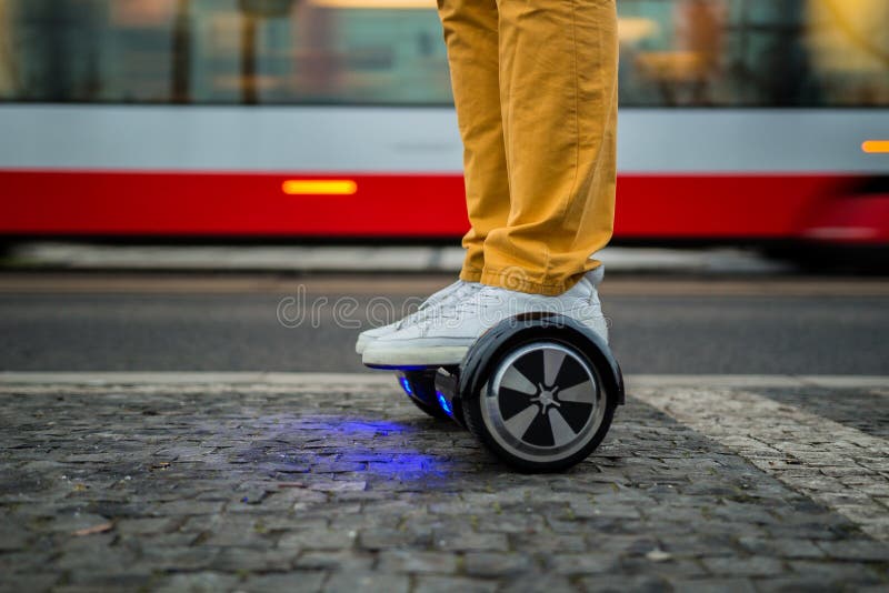 Uomo che usando hoverboard contro lo sfondo del tram fotografia stock libera da diritti Uomo che usando hoverboard contro lo sfondo del tram fotografia stock libera da diritti