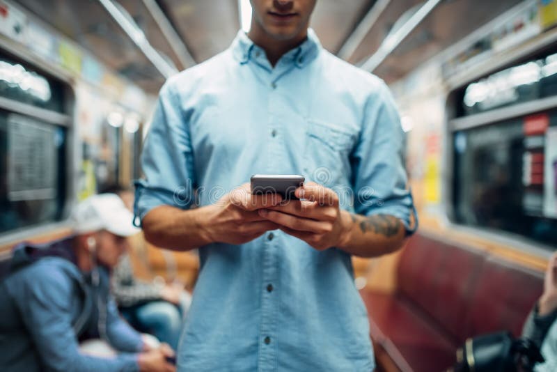 Young man using phone in subway car, addiction problem, social addicted people, modern underground lifestyle. Young man using phone in subway car, addiction problem, social addicted people, modern underground lifestyle