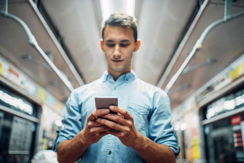 Young man using phone in subway car, addiction problem, social addicted people, modern underground lifestyle. Young man using phone in subway car, addiction problem, social addicted people, modern underground lifestyle