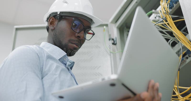 Uomo che utilizza un portatile mentre lavora in una stanza server stock footage