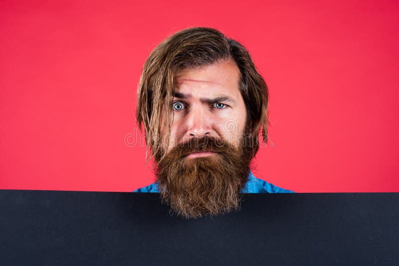 Uomo con barba seria e foglio di carta vuoto. servizio di barbiere. concetto di pubblicità. uomo brutale con la barba e immagine stock libera da diritti