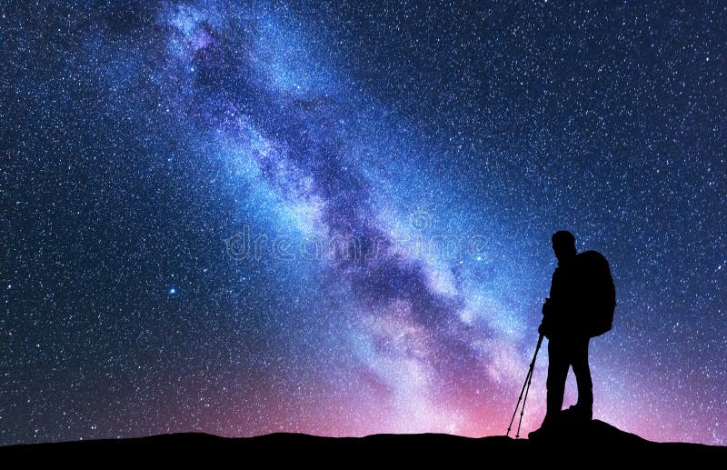 Uomo con i pali di trekking e dello zaino contro la Via Lattea fotografia stock Uomo con i pali di trekking e dello zaino contro la Via Lattea fotografia stock