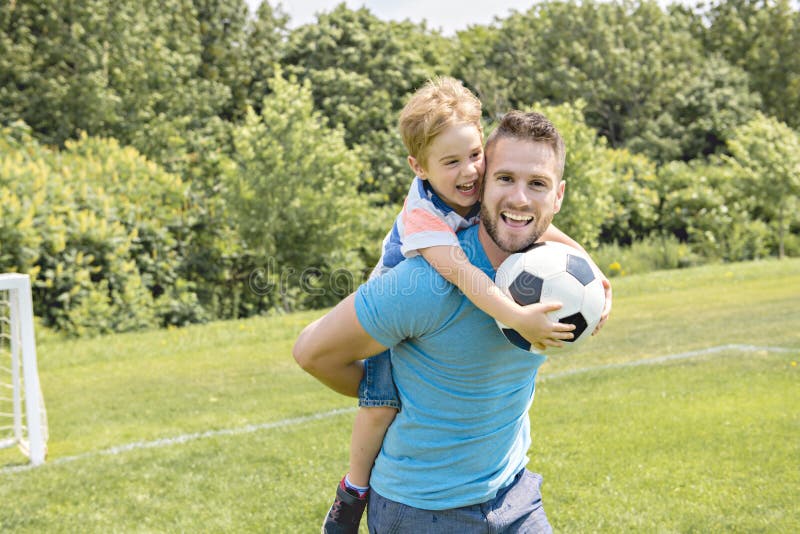 Uomo con il bambino che gioca a calcio fuori sul campo fotografie stock libere da diritti Uomo con il bambino che gioca a calcio fuori sul campo fotografie stock libere da diritti