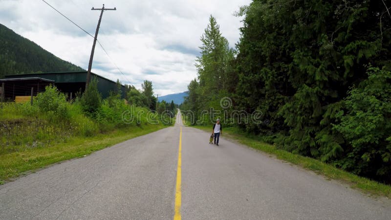 Uomo con il pattino che cammina sulla strada rurale 4k