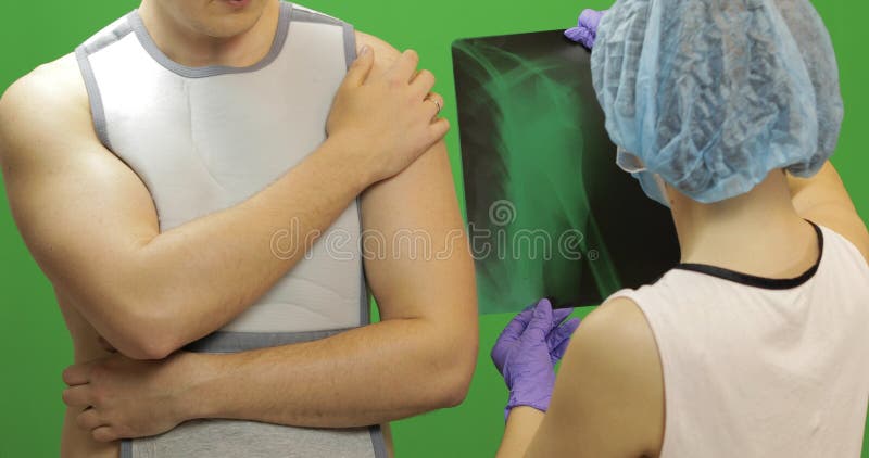 Uomo con la ferita sulla spalla L'infermiere esamina i raggi x Fasciatura per la spalla di riparazione immagine stock Uomo con la ferita sulla spalla L'infermiere esamina i raggi x Fasciatura per la spalla di riparazione immagine stock