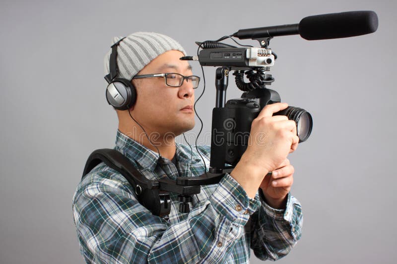 Uomo con la macchina fotografica di HD SLR e l'audio strumentazione fotografia stock libera da diritti Uomo con la macchina fotografica di HD SLR e l'audio strumentazione fotografia stock libera da diritti