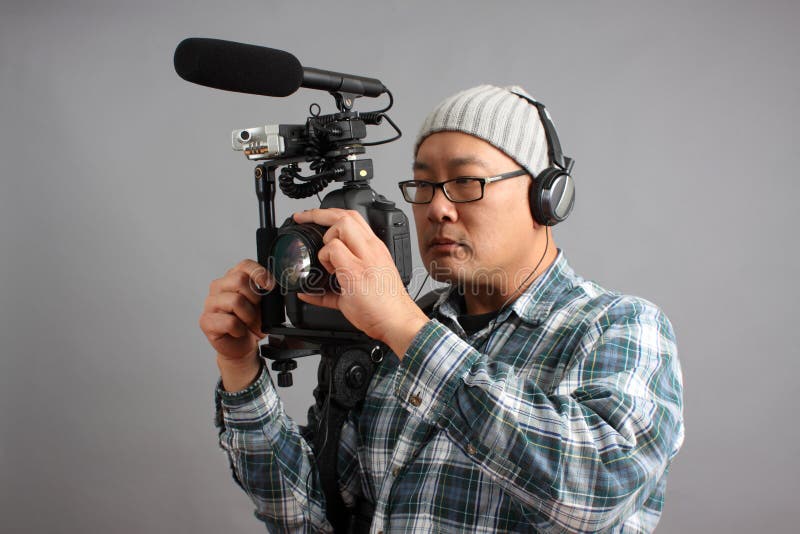 Uomo con la macchina fotografica di HD SLR e l'audio strumentazione fotografia stock libera da diritti Uomo con la macchina fotografica di HD SLR e l'audio strumentazione fotografia stock libera da diritti