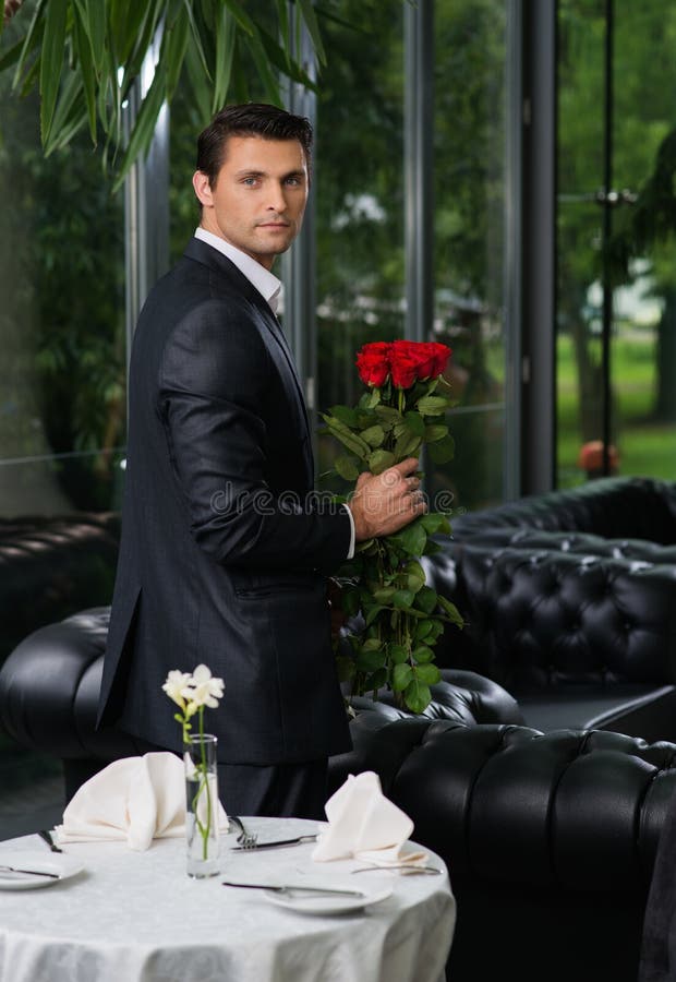Uomo con le rose in ristorante fotografia stock Uomo con le rose in ristorante fotografia stock