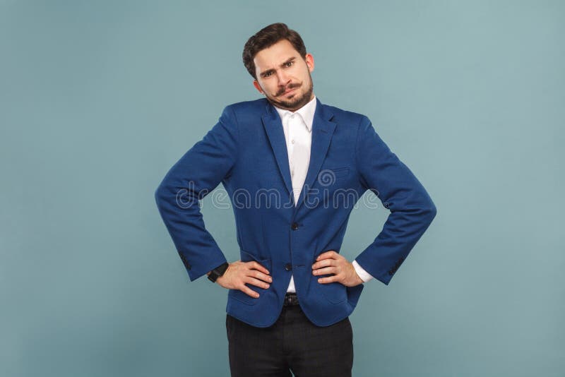 Well dressed confused man standing and looking at camera. Business people concept, richly and success. Indoor, studio shot on light blue background. Well dressed confused man standing and looking at camera. Business people concept, richly and success. Indoor, studio shot on light blue background