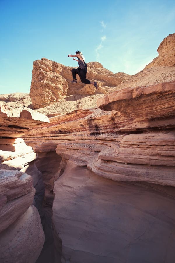 Uomo coraggioso che salta sopra la scogliera in canyon