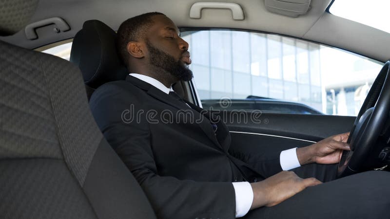 Uomo d'affari afroamericano sovraccarico che si siede in automobile, stanca dopo il giorno stressante immagini stock libere da diritti Uomo d'affari afroamericano sovraccarico che si siede in automobile, stanca dopo il giorno stressante immagini stock libere da diritti
