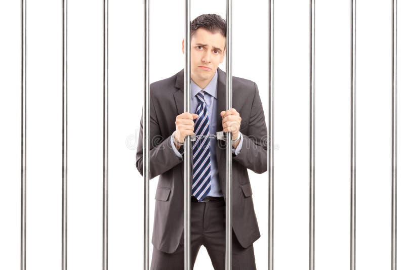Uomo d'affari ammanettato triste in vestito che posa nella prigione e che tiene le sedere fotografie stock Uomo d'affari ammanettato triste in vestito che posa nella prigione e che tiene le sedere fotografie stock